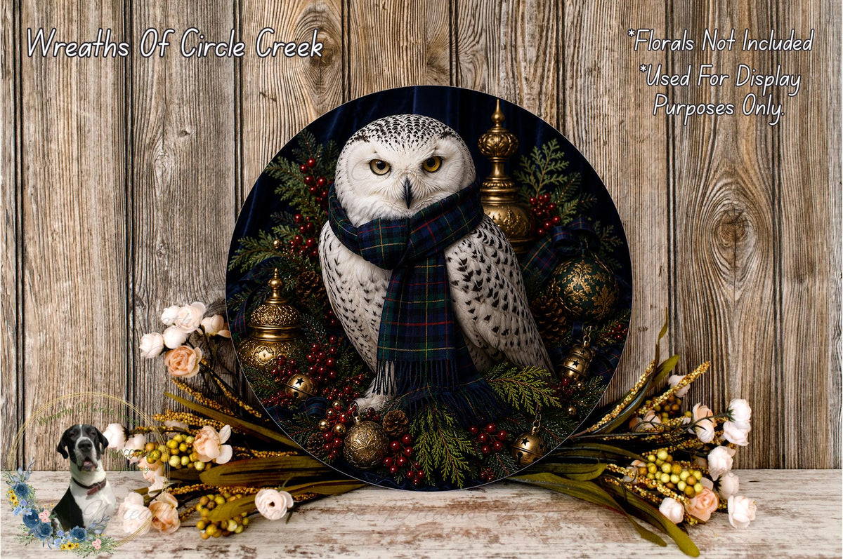 A decorative wreath featuring a white owl wearing a plaid scarf, surrounded by various holiday-themed elements such as berries, pine cones, and ornaments.