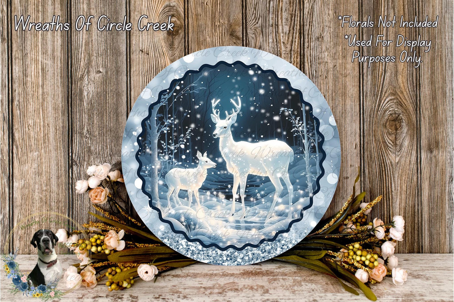 A decorative wreath featuring a snowy winter scene with two deer, surrounded by flowers and greenery, placed on a wooden surface.