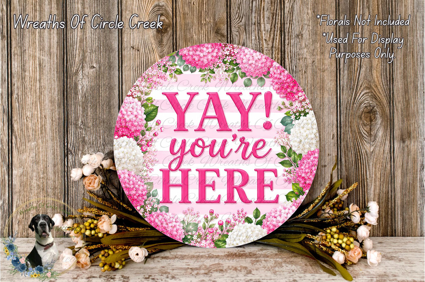A round floral wreath with the text "YAY! you're here" in pink and white colors, surrounded by various flowers and greenery.
