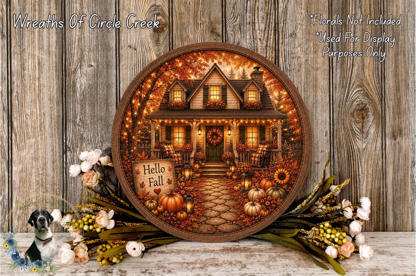A round wooden frame displaying a painting of a house surrounded by fall decorations, including pumpkins, flowers, and a wreath.