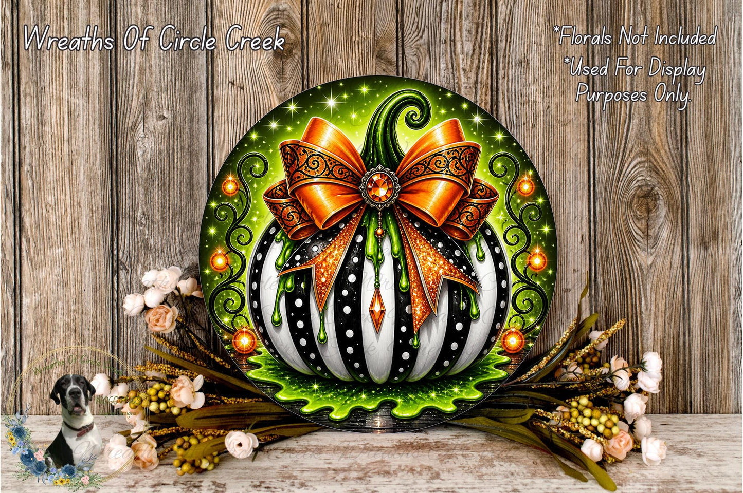 a decorative pumpkin with a large orange bow, surrounded by a floral arrangement and placed on a wooden surface.