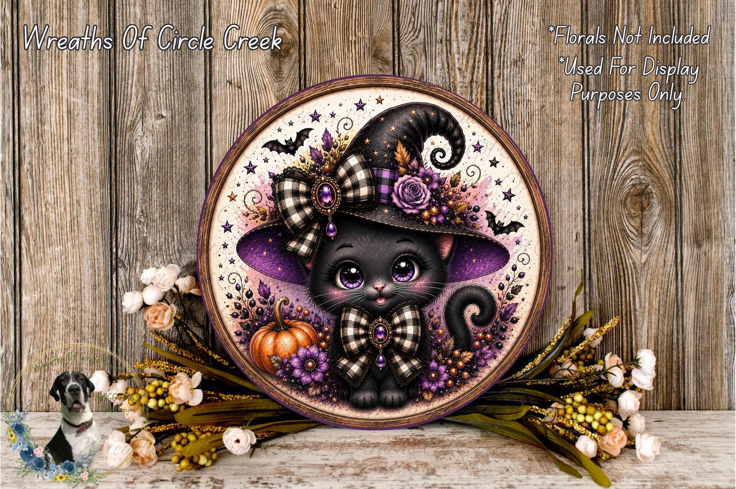 A decorative wreath featuring a black cat wearing a witch's hat, surrounded by autumn foliage and flowers.