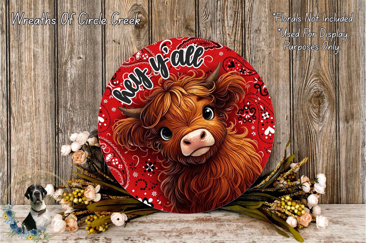 a large red circular sign with a cartoon cow's face, surrounded by flowers and placed on a wooden surface.