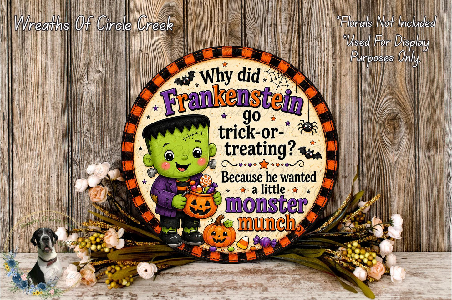 A Halloween-themed sign featuring a green-skinned Frankenstein monster holding a pumpkin and candy, with a question about why he went trick-or-treating. The sign is surrounded by a wreath of flowers and a wooden background.