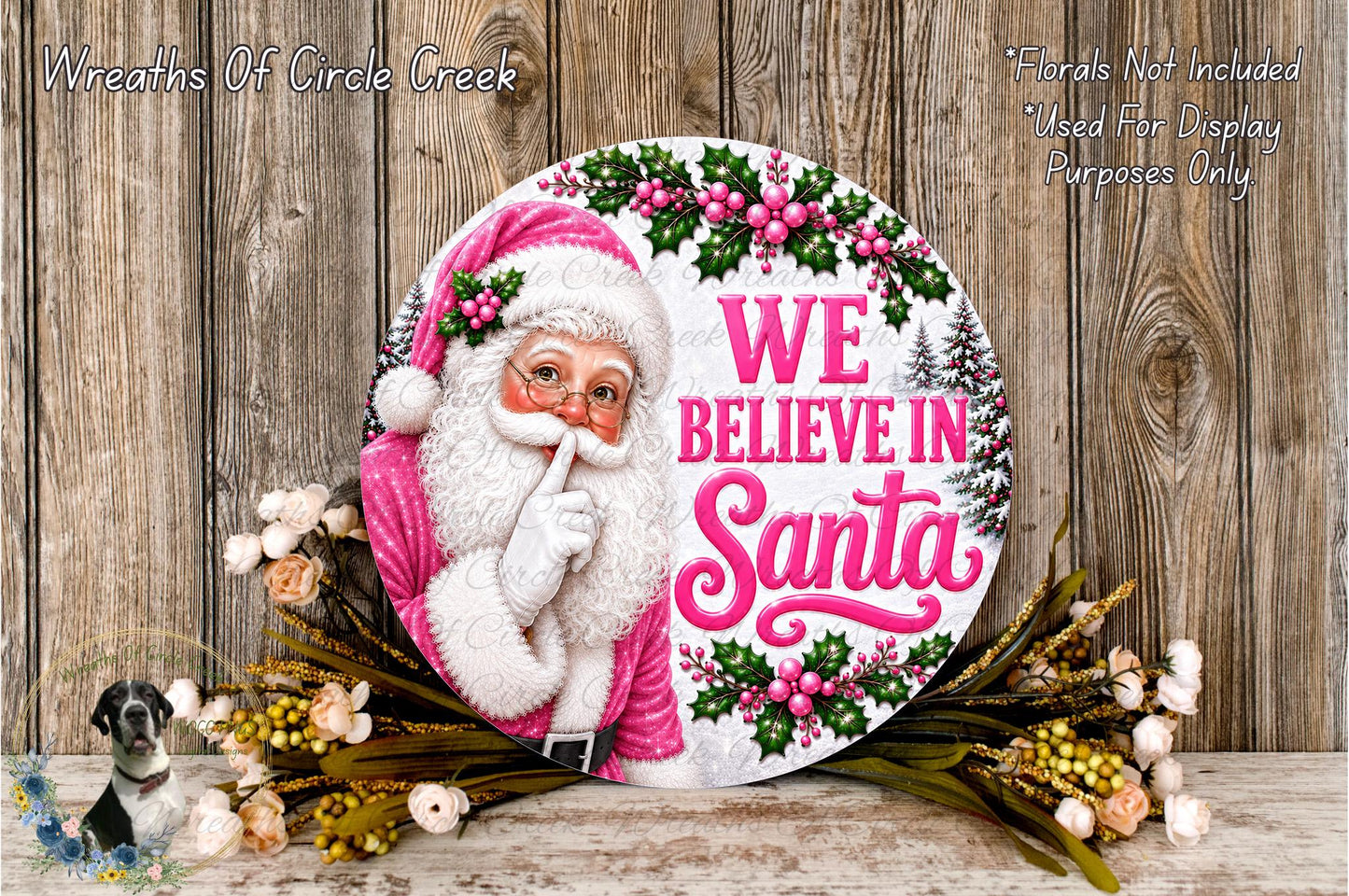 A round sign featuring a Santa Claus figure with the text "WE BELIEVE IN Santa" and surrounded by flowers and greenery.