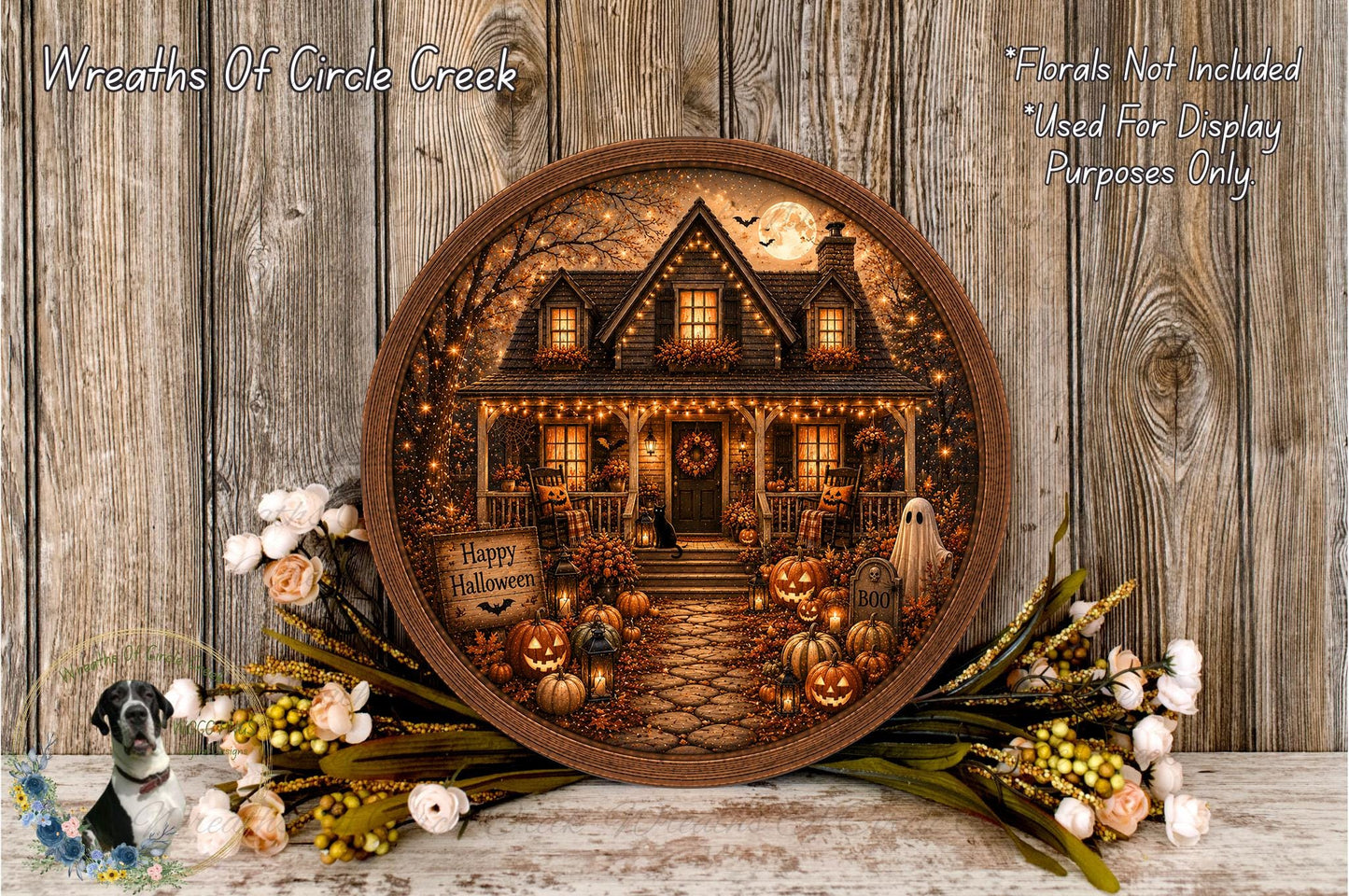 A round wooden frame displaying a Halloween-themed scene with a house, pumpkins, and a ghost, surrounded by flowers and greenery.