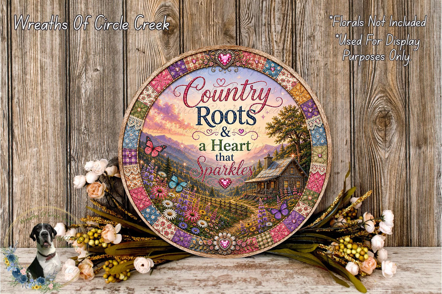 a decorative plate with a countryside scene, surrounded by flowers and placed on a wooden surface.