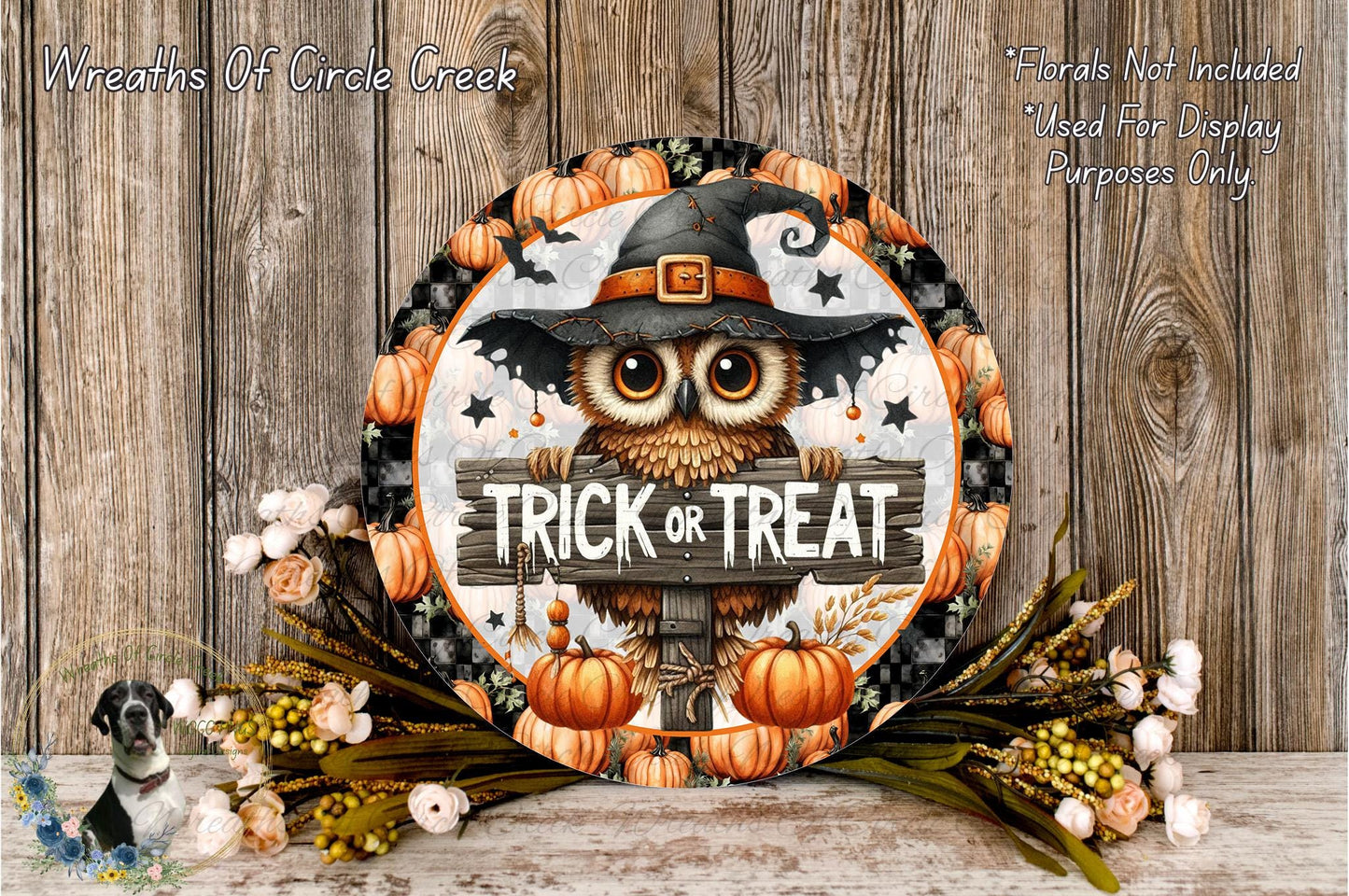A Halloween-themed wreath with an owl wearing a witch's hat and holding a sign that says "Trick or Treat". The wreath is surrounded by pumpkins and flowers, creating a festive atmosphere.