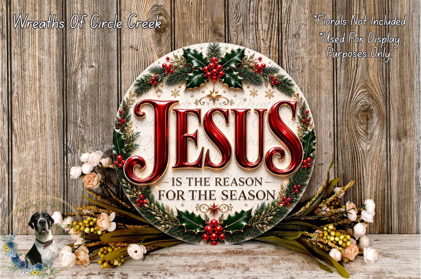 a circular sign with the text "JESUS IS THE REASON FOR THE SEASON" surrounded by a wreath of holly, berries, and other holiday decorations. The sign is placed on a wooden surface, and there are additional floral arrangements in the background.