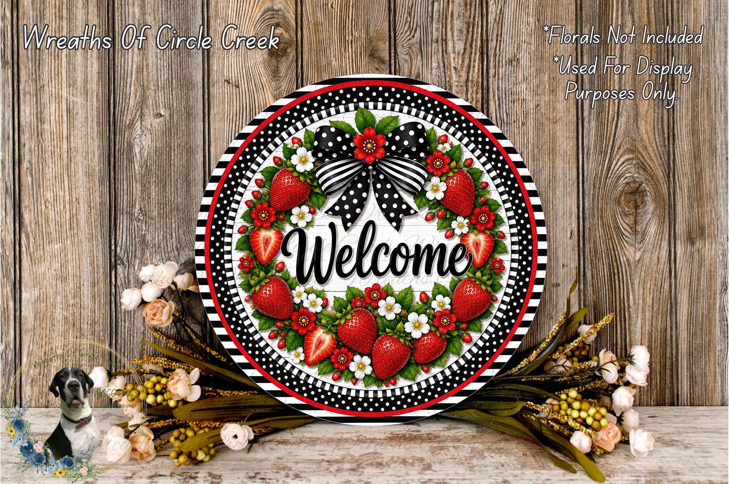 A decorative wreath with a welcoming message, surrounded by flowers and greenery, placed on a wooden surface.