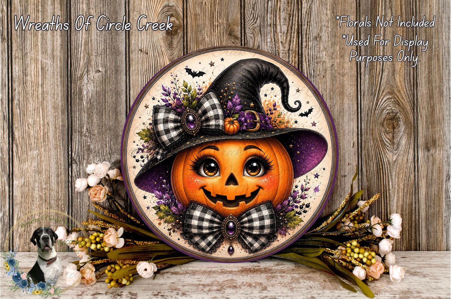 A Halloween-themed wreath featuring a carved pumpkin with a witch's hat and bow, surrounded by flowers and placed on a wooden surface.