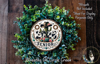 A wreath made of green leaves and flowers, with a circular sign that reads "2020 SENIOR" in the center.