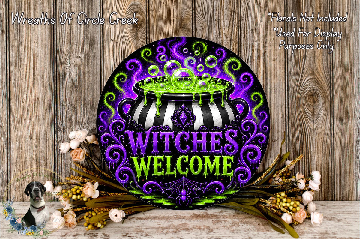 A decorative sign with the text "WITCHES WELCOME" in a colorful, whimsical style, surrounded by flowers and a cauldron.