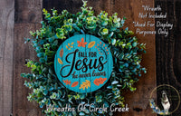 a wreath made of green leaves and a wooden sign with the text "Fall for Jesus he never leaves" against a wooden background.