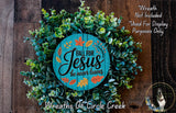 a wreath made of green leaves and a wooden sign with the text "Fall for Jesus he never leaves" against a wooden background.