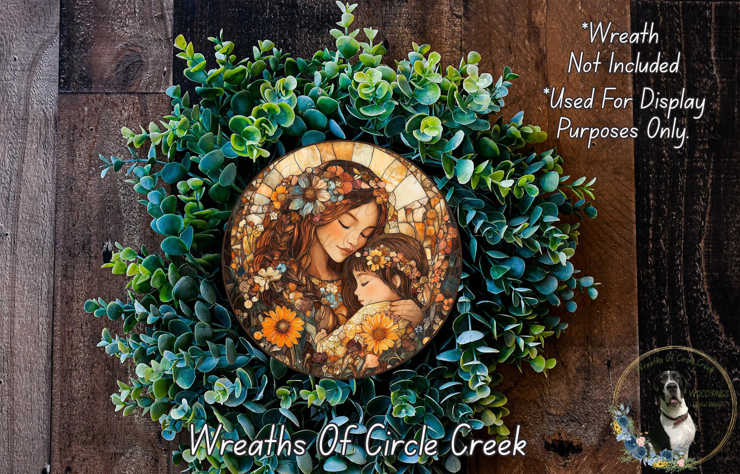 A wreath made of green leaves and flowers, with a circular medallion featuring a woman and a child in the center.