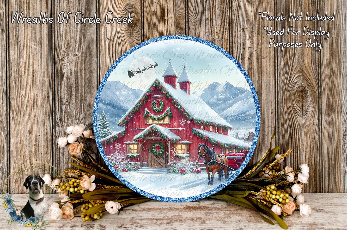 A round, decorative plate featuring a winter scene with a red barn, a horse, and snow-covered mountains in the background. The plate is surrounded by a wreath of flowers and greenery, and the text "Wreaths Of Circle Creek" and "Flowers Not Included Used For Display Purposes Only" is visible.