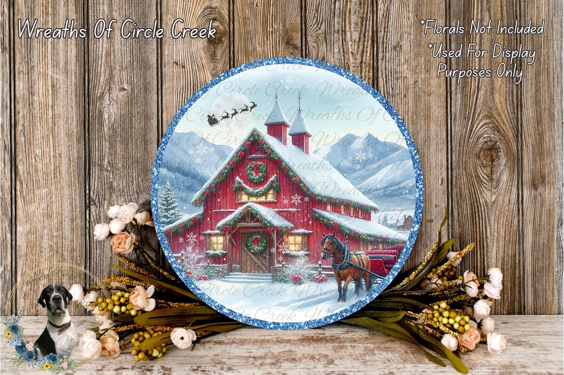 A round, decorative plate featuring a winter scene with a red barn, a horse, and snow-covered mountains in the background. The plate is surrounded by a wreath of flowers and greenery, and the text "Wreaths Of Circle Creek" and "Flowers Not Included Used For Display Purposes Only" is visible.