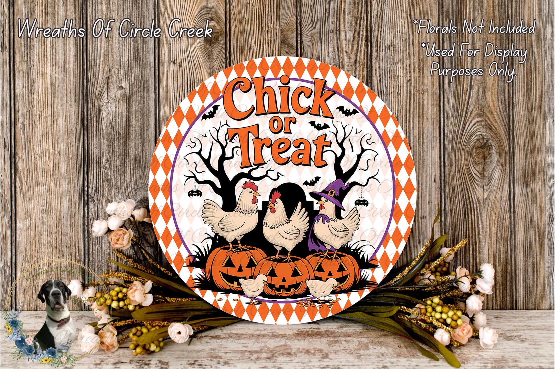 a Halloween-themed sign with a chicken and pumpkin design, surrounded by flowers and placed on a wooden surface.