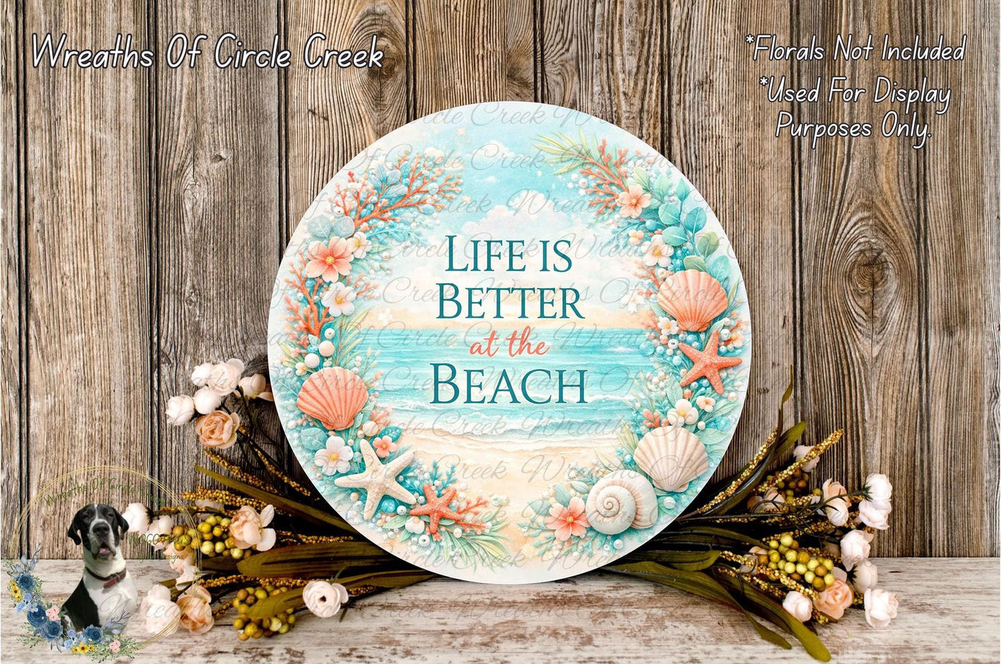 a round sign with a beach-themed design, surrounded by a wreath of seashells, starfish, and other beach-related items. The sign has the text "Life is Better at the Beach" written on it.