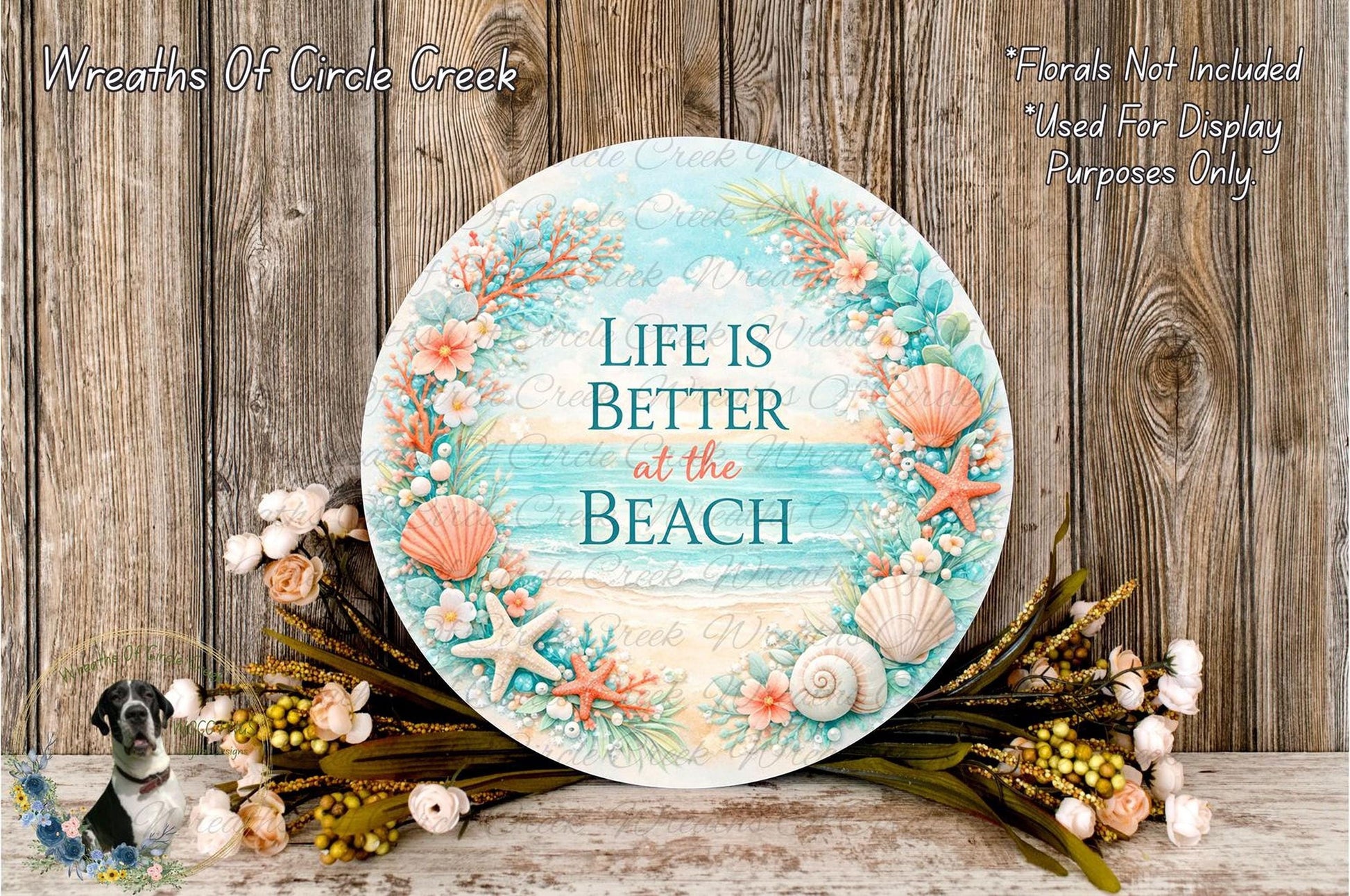 a round sign with a beach-themed design, surrounded by a wreath of seashells, starfish, and other beach-related items. The sign has the text "Life is Better at the Beach" written on it.