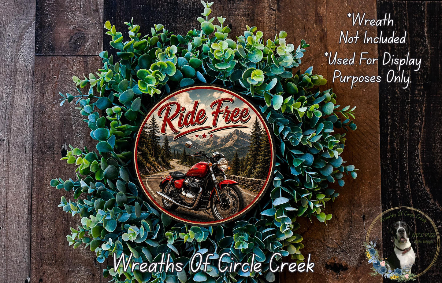 a wreath with a red motorcycle and a scenic mountain landscape, surrounded by green foliage.