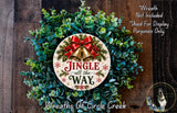 a Christmas wreath with a decorative sign that says "Jingle all the Way". The wreath is made of green leaves and has a red ribbon and bells attached to it. The sign is placed in the center of the wreath. The background of the image is a wooden surface with a dog visible in the bottom right corner.