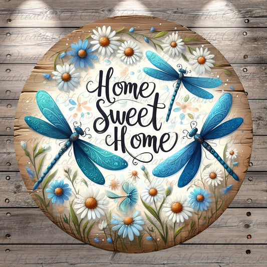 A circular wooden sign with a floral design and two blue dragonflies. The sign has the text "Home Sweet Home" written on it.