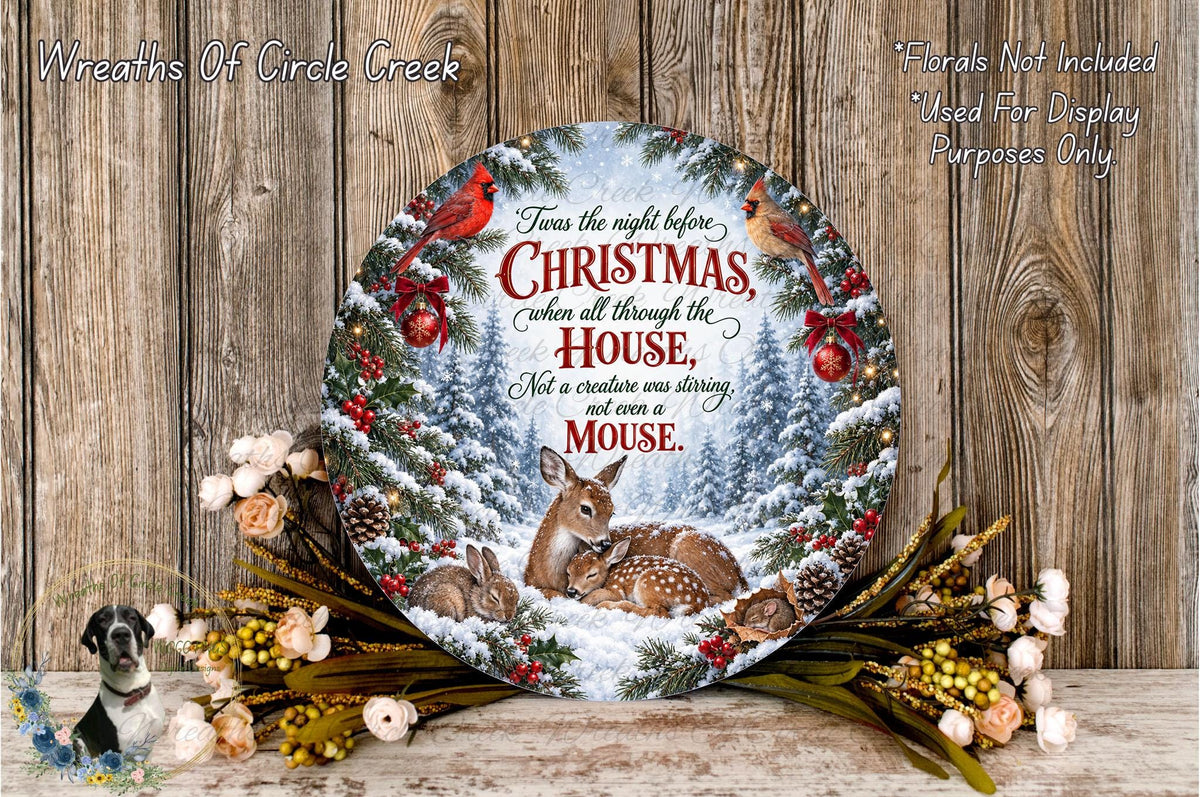 a decorative wreath with a winter scene, including a deer, rabbits, and pine trees, surrounded by flowers and greenery. The wreath is displayed on a wooden surface, and there is a text overlay that reads "Twas the night before Christmas when all through the house was stirring, not a creature was stirring as a mouse."