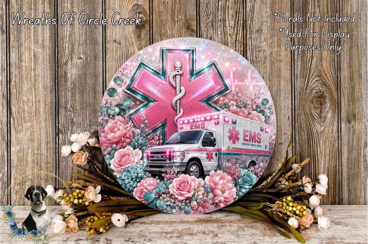 a round, decorative plate with a white ambulance and a pink cross, surrounded by flowers and greenery.