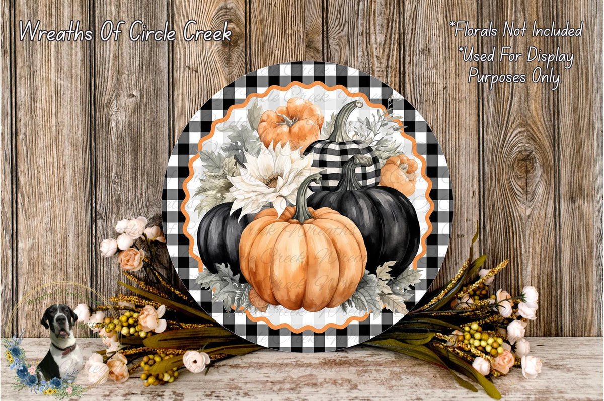 a decorative plate with a black and white checkered border, surrounded by a floral arrangement and pumpkins, set against a wooden background.
