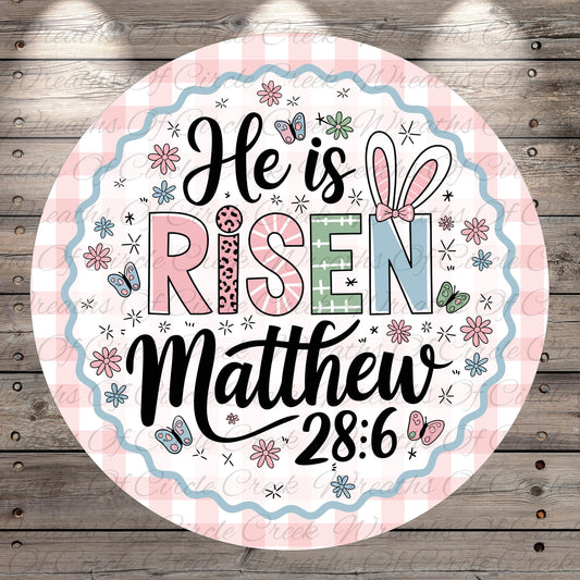 A circular design with a pink and white checkered border, featuring the text "He is Risen Matthew 28:6" surrounded by various Easter-themed elements such as flowers, butterflies, and Easter eggs.