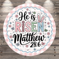 A circular design with a pink and white checkered border, featuring the text &quot;He is Risen Matthew 28:6&quot; surrounded by various Easter-themed elements such as flowers, butterflies, and Easter eggs.