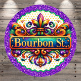 a circular sign with a decorative border and a vibrant, colorful design. The sign prominently displays the text "Bourbon St.", surrounded by a glittery purple border.