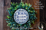 a wreath made of green leaves and a circular sign with the text "Jesus is the reason for the season" on it, placed on a wooden surface.