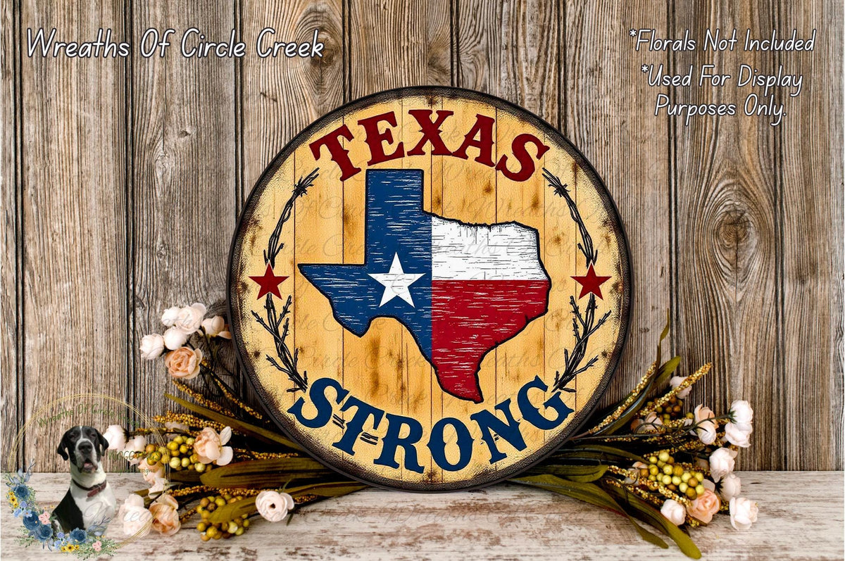 A wooden sign with the text "TEXAS STRONG" and a Texas state map, surrounded by flowers and greenery, against a wooden background.