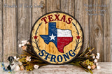 A wooden sign with the text "TEXAS STRONG" and a Texas state map, surrounded by flowers and greenery, against a wooden background.