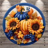 A circular arrangement of sunflowers, pumpkins, and blueberries on a blue background, with autumn leaves surrounding them.