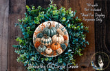 a wreath made of various autumn-themed elements, including pumpkins, gourds, and greenery. The wreath is displayed on a wooden surface, and there is a small dog in the bottom right corner of the image.