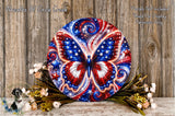 a large, colorful butterfly-shaped wreath with red, white, and blue colors, surrounded by flowers and placed on a wooden surface.
