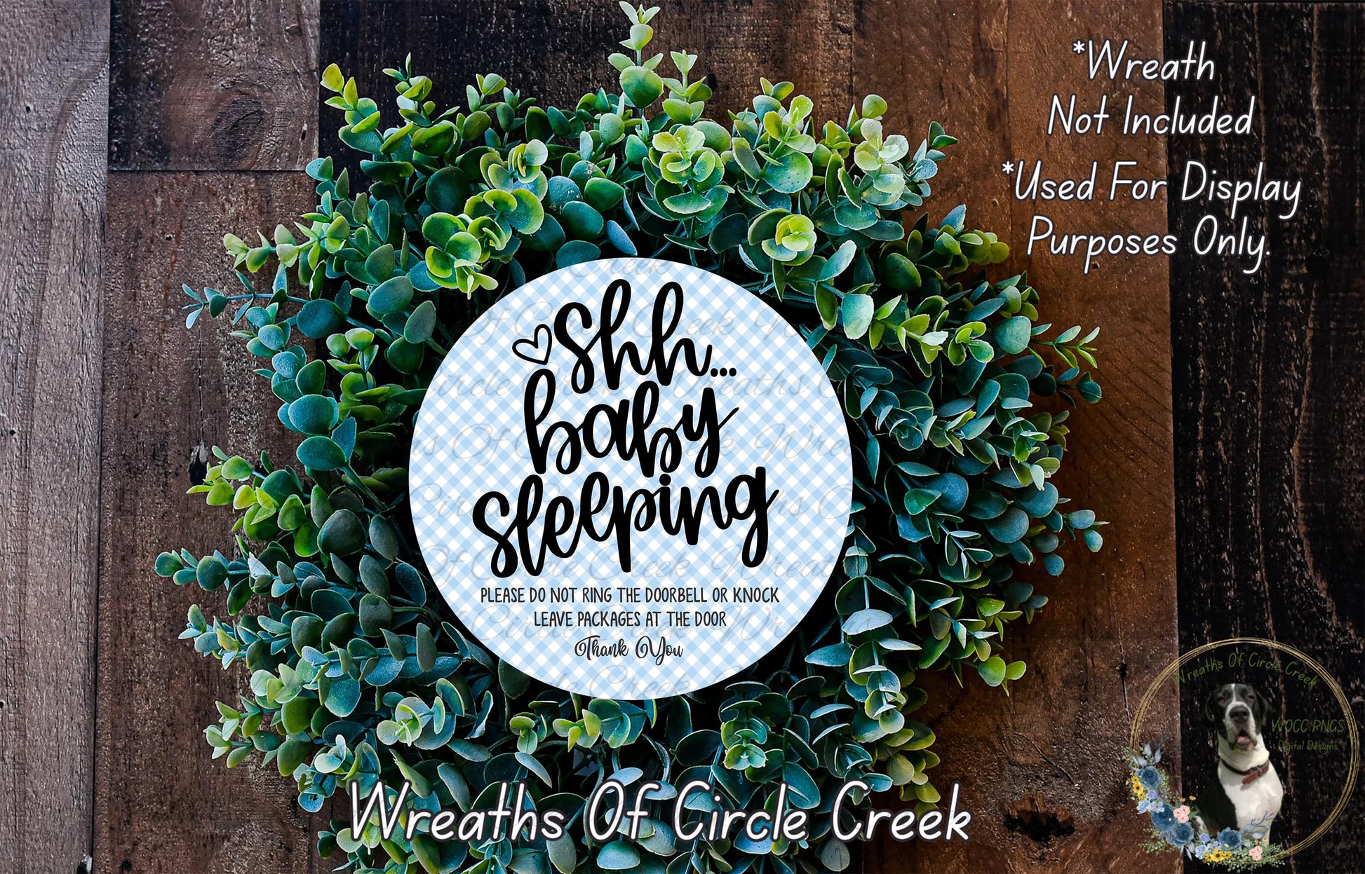 a wreath made of green leaves and a circular sign with text on it, placed on a wooden surface.
