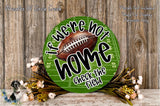 a green football field sign with the text "If we're not home, check the field" displayed on it. The sign is surrounded by a floral arrangement and a wooden background.
