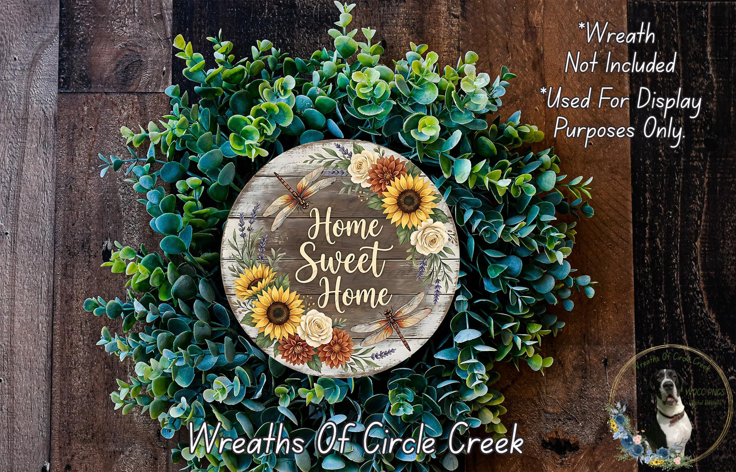 a wreath made of various green plants and flowers, with a wooden sign that reads "Home Sweet Home" in the center.