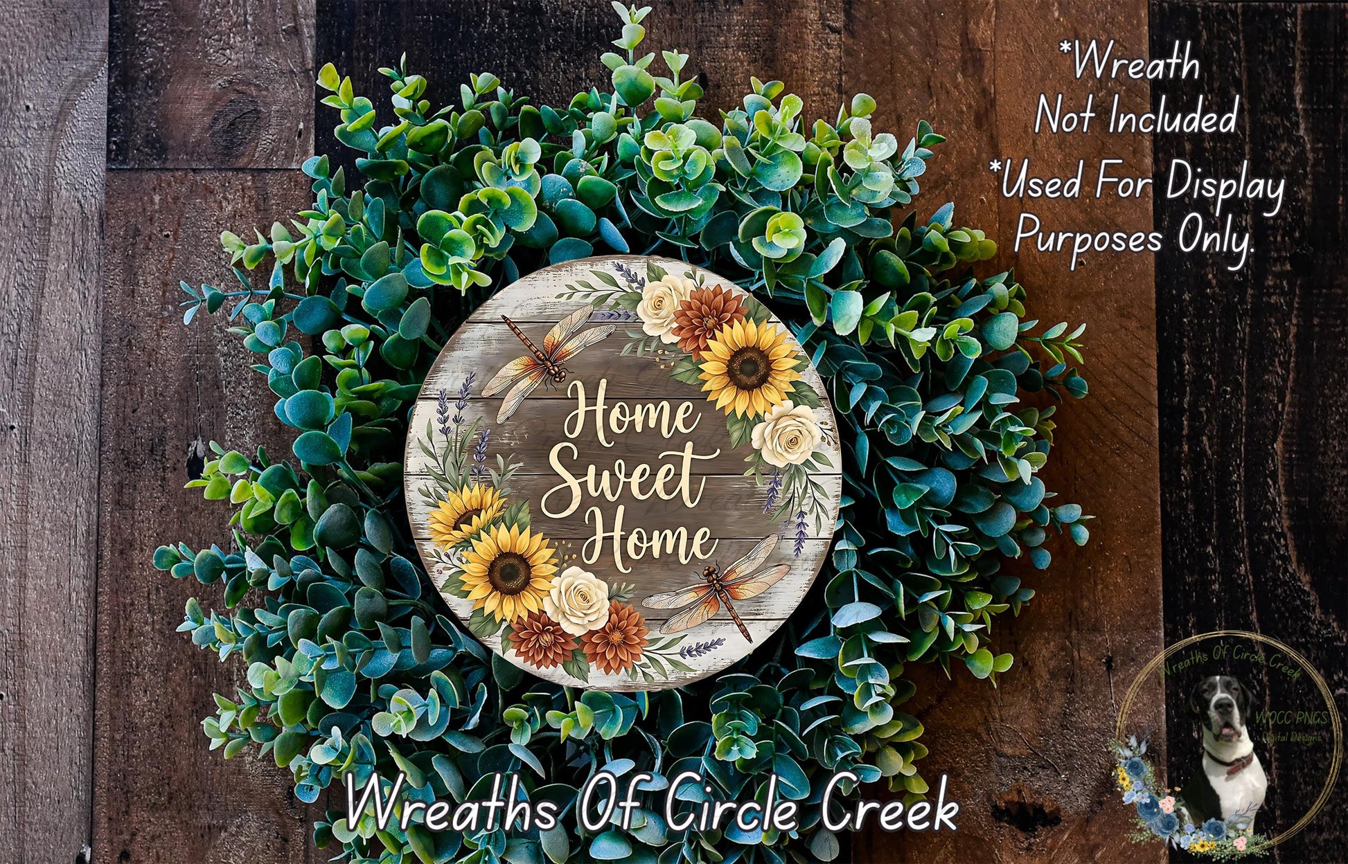 a wreath made of various green plants and flowers, with a wooden sign that reads "Home Sweet Home" in the center.