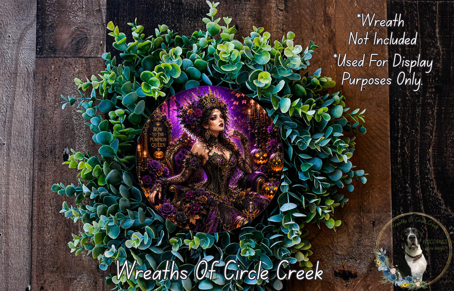 a wreath with a woman in a purple dress and a crown, surrounded by green leaves and flowers. The wreath is displayed on a wooden surface, and there is a small dog in the bottom right corner of the image.