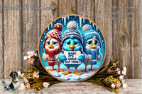 A decorative plate featuring three cartoon birds wearing winter hats and scarves, holding a sign that says "Baby It's cold here!" The plate is set against a snowy background and is surrounded by flowers.
