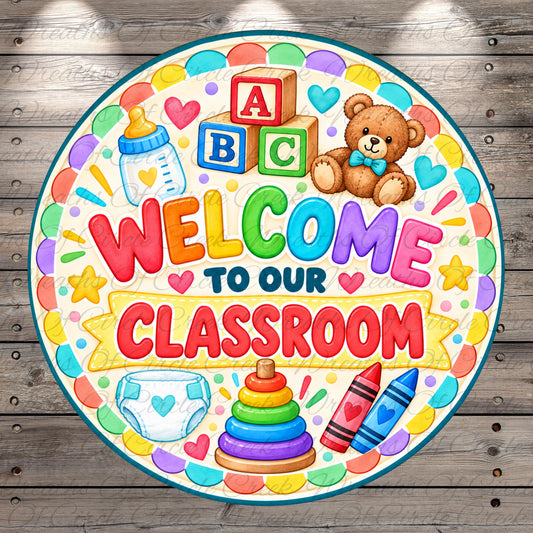 The image is a colorful welcome sign for a classroom, featuring various children's items such as a teddy bear, baby bottle, crayons, and a stack of rings.