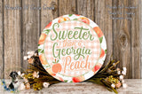 a decorative sign with the text "Sweeter than a Georgia Peach" surrounded by a floral arrangement and a wooden background.