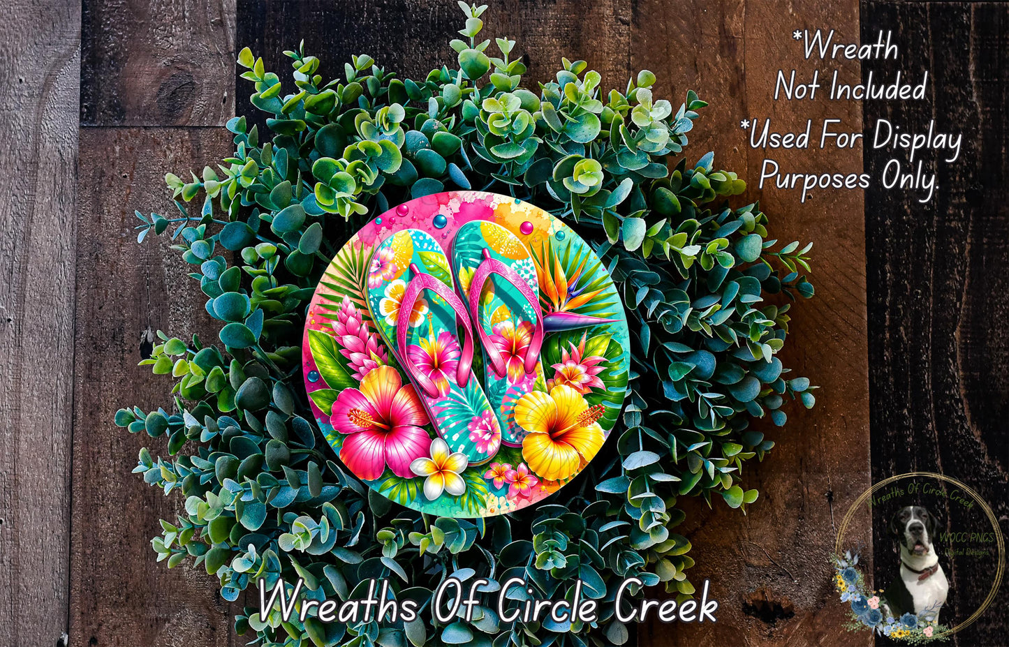 A colorful wreath made of various plants and flowers, including hibiscus, eucalyptus, and other tropical foliage. The wreath is adorned with a pair of flip-flops, adding a playful and whimsical touch. The image is described as a "Wreath of Circle Creek" and is not included in a display for purposes other than decoration.