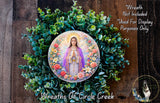 A wreath featuring a circular image of the Virgin Mary surrounded by colorful flowers and greenery.